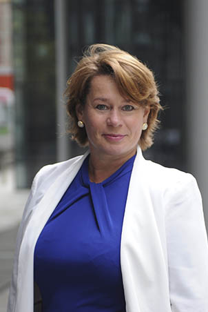 Portrait of Michelle Thomson, wearing a white jacket over a blue top